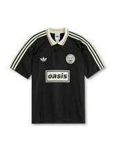 Front view of Oasis Live ’25 black collared shirt with off-white stripes, trefoil chest logo, circular crest, and boxed oasis graphic.