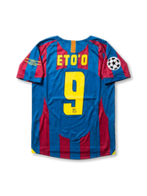 Front view of Barcelona 2005-06 Paris Final home shirt with blaugrana stripes, club crest, yellow detailing, Champions League patch, and final sleeve embroidery.