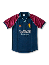 Front view of West Ham United Iron Maiden Brave New World special edition shirt with dark teal body, claret sleeves, Maiden branding, Eddie graphic, and club crest.