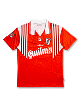 Front view of River Plate 1995-96 away shirt with red body, white shoulder striping, Quilmes sponsor, club crest, and Adidas detailing.