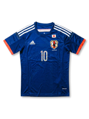 Front view of Japan Captain Tsubasa special edition shirt with blue body, JFA crest, Japan flag detail, orange sleeve trim, and illustrated #10 front number.
