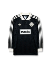 Front view of Adidas Originals x Oasis Live ’25 black long sleeve shirt with white collar, trefoil logo, Oasis chest graphic, and circular Live ’25 patch.