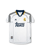 Front view of Real Madrid 1998-00 home shirt with white base, Teka sponsor, navy-and-gold collar trim, adidas logo, and club crest.