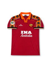 Front view of AS Roma 1998-99 home shirt with red body, orange collar, wolf-pattern shoulder panels, INA Assitalia sponsor, and club crest.