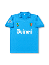Front view of Napoli 1987-88 home shirt with sky-blue body, Buitoni sponsor, Scudetto shield, Napoli sleeve patch, and fold-over collar.