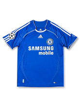 Front view of Chelsea 2006-07 home shirt with royal blue body, Samsung Mobile sponsor, Chelsea crest, white shoulder stripes, and UEFA Champions League sleeve patch.