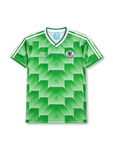 Front view of Germany 1990 World Cup away shirt with green geometric pattern, Germany crest, white V-neck collar, and white shoulder stripes.