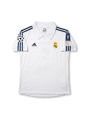 Front view of Real Madrid 1998-00 home shirt with white base, club crest, dark navy shoulder stripes, and Champions League sleeve patch.