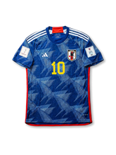 Front view of Japan 2022 World Cup home shirt with blue origami-inspired pattern, Japan crest, yellow #10 print, red trim, and Qatar 2022 sleeve patch.