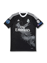 Front view of Real Madrid 2014-15 Yohji Yamamoto black third jersey with dragon graphic, Fly Emirates sponsor, monochrome club crest, Champions League sleeve patches, and white shoulder stripes.