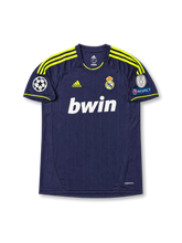 Front view of Real Madrid 2012-13 away shirt with dark navy base, neon yellow shoulder stripes, Real Madrid crest, bwin sponsor, and Champions League sleeve patch detailing.