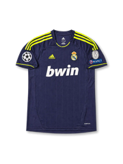 Front view of Real Madrid 2012-13 away shirt with dark navy base, neon yellow shoulder stripes, Real Madrid crest, bwin sponsor, and Champions League sleeve patch detailing.
