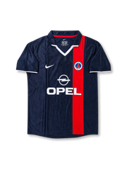Front view of Paris Saint-Germain 2001-02 home shirt with navy base, red vertical center stripe, PSG crest, Opel sponsor, white collar detail, and short sleeves.