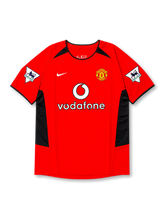 front view of Manchester United 2002-04 home shirt with red base, black side panels, Vodafone sponsor, club crest, and Premier League sleeve patches