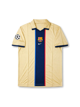 Barcelona 1999-00 away jersey front view with champagne-gold body, central navy stripe, club crest, and Champions League sleeve patch.