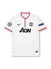 ront view of Manchester United 2012-13 away shirt with white body, red trim, Aon sponsor, club crest, Champions League patch, and UEFA Respect sleeve patch