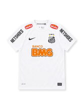 Santos 2011-12 home jersey, front view, white with crew neck, black Nike swoosh, striped club crest with centenary crown and stars, orange Banco BMG sponsor, Seara shoulder patches, Netshoes sleeve logos