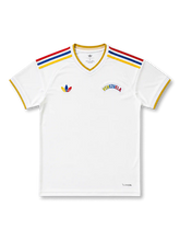 Venezuela 2026/27 away shirt with a white body, yellow-trim V-neck, red-blue-yellow shoulder stripes, heritage-style Trefoil chest branding, arched Venezuela wordmark, and La Vinotinto back-neck text.