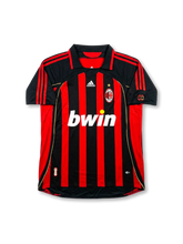 Front view of AC Milan home shirt in black and red stripes with bwin sponsor, adidas logo, club crest, gold star, and sleeve patches.