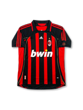 Front view of AC Milan home shirt in black and red stripes with bwin sponsor, adidas logo, club crest, gold star, and sleeve patches.