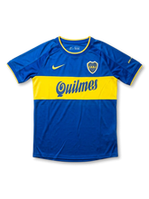 Front view of Boca Juniors home shirt in blue with yellow chest band, Quilmes sponsor, yellow swoosh, and CABJ crest.