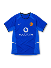 Manchester United 2002/03 royal-blue third jersey with lighter blue side panels, black-trimmed round collar, white Nike Swoosh, club crest and white Vodafone sponsor.