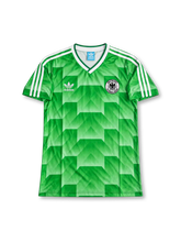 ドイツ代表 1990年 ワールドカップ アウェイユニフォーム ローター・マテウス10番。adidas製グリーンのボディ全体に幾何学模様を施し、ホワイトのVネックと肩のスリーストライプ、胸元にadidasのトレフォイルロゴとドイツサッカー連盟のエンブレムを配したレトロサッカージャージ。