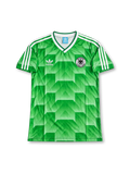Front view of Germany 1990 World Cup away shirt with green geometric pattern, Germany crest, white V-neck collar, and white shoulder stripes.