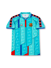 FCバルセロナ 1996/97シーズン アウェイユニフォーム ロナウド9番。Kappa製のターコイズブルーのボディに、ネイビーの幾何学的なラインとレッド・ブルーの縦ライン、ブルーの襟を組み合わせたレトロサッカージャージ。生地全体にBarçaの文字とKappaロゴの総柄を施し、肩から袖にかけてKappaのロゴテープを配置。胸元にはホワイトのKappaロゴとクラブエンブレム、背面にはRONALDOのネームとホワイトの9番を配したデザイン。