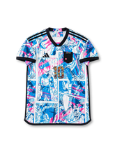 日本代表 ドラゴンボール超 コラボデザイン 10番 スペシャルエディション サッカーユニフォーム。ホワイトのボディ全体にブルーとピンクの漫画コマ風グラフィックを配し、ブラックのVネック、袖口、肩のスリーストライプを組み合わせたデザイン。胸元にはJAPANの文字入りエンブレムとキャラクターイラストを組み込んだ10番を配置し、背面にはドラゴンボール超のロゴと漫画キャラクター柄の大型10番をあしらったサッカージャージ。