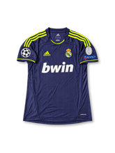 レアル・マドリード 2012/13シーズン アウェイユニフォーム クリスティアーノ・ロナウド7番。adidas製のダークネイビーのボディに細かな縦ラインの織り柄、蛍光イエローの肩のスリーストライプ、襟元と袖口のアクセントを組み合わせたレトロサッカージャージ。胸元には蛍光イエローのadidasロゴ、レアル・マドリードのクラブエンブレム、ホワイトのbwinスポンサーロゴを配置。袖にはUEFAチャンピオンズリーグ、RESPECT、欧州9度制覇の記念パッチを備え、背面にはRONALDOのネームとホワイトの7番を配したデザイン。