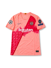 FCバルセロナ 2018-19シーズン サードユニフォーム リオネル・メッシ10番 Nike製 コーラルピンクのボディにダークレッドの斜めラインと都市の街並みをモチーフにしたグラフィック、Rakutenスポンサーロゴ、クラブエンブレム、UEFAチャンピオンズリーグの袖章、背面にMESSIのネームと10番を配したレトロサッカージャージ