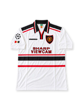 Manchester United 1997-99 away jersey featuring David Beckham #7, Umbro white shirt with black and red horizontal chest stripes, black fold-over collar, Sharp Viewcam sponsor logo, Manchester United club crest, UEFA Champions League sleeve patch, and BECKHAM name and number 7 on the back of this retro soccer jersey.