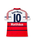 Bayern Munich 1998-00 away jersey featuring Lothar Matthaus #10, adidas soccer shirt with a white upper body, red lower section, navy horizontal stripes, red polo collar, red three-stripe shoulder detailing, black OPEL sponsor logo, Bayern Munich crest, and Bayern München lettering with Matthäus name and navy number 10 on the back.