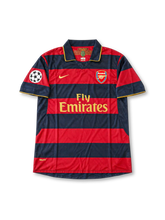 Arsenal 2007-08 third jersey with Dennis Bergkamp #10 tribute printing, Nike navy and burgundy horizontal striped soccer shirt featuring a gold-trimmed polo collar and sleeve cuffs, gold Nike Swoosh, Fly Emirates sponsor, Arsenal club crest, UEFA Champions League sleeve patch, and BERGKAMP name with gold number 10 on the back. Commemorative player printing, not a Bergkamp match-worn season jersey.