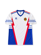 Yugoslavia 1998 FIFA World Cup away jersey featuring Dragan Stojkovic #10, adidas white soccer shirt with blue side panels and shoulder stripes, red geometric accents, blue V-neck collar, adidas branding, Yugoslavia national team crest, and STOJKOVIC name and number 10 on the back.