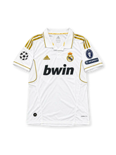 Real Madrid 2011-12 home jersey featuring Angel Di Maria #22, adidas white soccer shirt with gold three-stripe shoulder detailing, gold-trimmed polo collar, black bwin sponsor logo, Real Madrid club crest, UEFA Champions League and Respect sleeve patches, and DI MARÍA name with gold number 22 on the back.