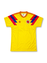 Colombia 1990 FIFA World Cup home jersey featuring Carlos Valderrama #10, yellow adidas soccer shirt with bold red and blue geometric shoulder and sleeve graphics, tricolor collar trim, adidas Trefoil logo, Colombia national team crest, and VALDERRAMA name with red number 10 on the back.