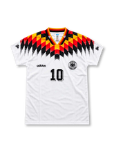 Germany 1994 FIFA World Cup home jersey featuring Lothar Matthaus #10, white adidas soccer shirt with bold black, red and yellow diamond patterns across the shoulders and upper chest, German flag-colored collar and sleeve trim, black adidas logo, Germany DFB crest, black front number 10, and MATTHÄUS name with number 10 on the back.