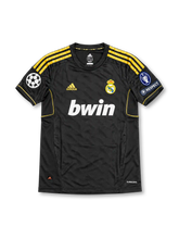 Real Madrid 2011-12 away jersey featuring Angel Di Maria #22, black adidas soccer shirt with gold three-stripe shoulder detailing, gold adidas logo and piping, white bwin sponsor, Real Madrid club crest, UEFA Champions League and Respect sleeve patches, and DI MARÍA name with gold number 22 on the back.
