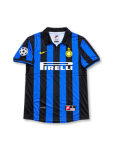 Front view of the 1998/99 Inter Milan home soccer jersey featuring black and blue vertical stripes, a yellow Nike Swoosh, Inter crest with gold star, white Pirelli sponsor, and UEFA Champions League sleeve patch.