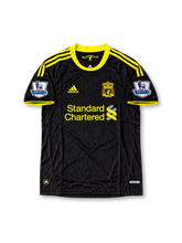 Front view of the 2010/11 Liverpool black and yellow third soccer jersey by adidas, featuring yellow three-stripe shoulder detailing, the Liverpool crest, Standard Chartered sponsor, and Barclays Premier League sleeve patches.