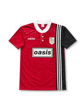 Front view of the red and black Oasis x adidas Boltmakers Arms FC football jersey inspired by the 1995/96 team kit, featuring a white collar, adidas three stripes, Boltmakers Arms crest, and boxed Oasis logo.