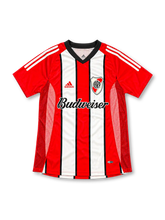 Front view of the River Plate 2002/03 red and white striped away soccer jersey featuring a black V-neck collar, red adidas shoulder stripes, club crest, Budweiser sponsor, and textured mesh side panels.
