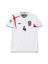 England 2005-07 white Umbro home jersey featuring asymmetric red St George's Cross detailing, navy trim, Three Lions crest, Germany 2006 World Cup sleeve patch and Steven Gerrard number 4.