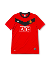 Manchester United 2009/10 red home jersey featuring a black chest chevron, white Nike logo, AIG sponsor, and club crest, front view.