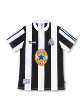 Newcastle United 1995/97 black-and-white striped home jersey with adidas logo, buttoned white collar, club crest, and Newcastle Brown Ale sponsor, front view.