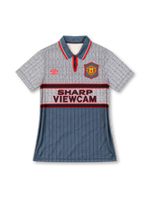 Manchester United 1995/96 grey third jersey with patterned upper panels, red Umbro logo, club crest, and Sharp Viewcam sponsor, front view.