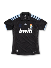 Real Madrid 2009/10 black away jersey featuring pale-blue adidas shoulder stripes, white bwin.com sponsor, and crowned club crest, front view.