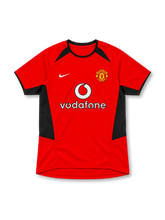 Manchester United 2002–04 red home short-sleeve jersey with black side panels, white Nike Swoosh, club crest and Vodafone sponsor.